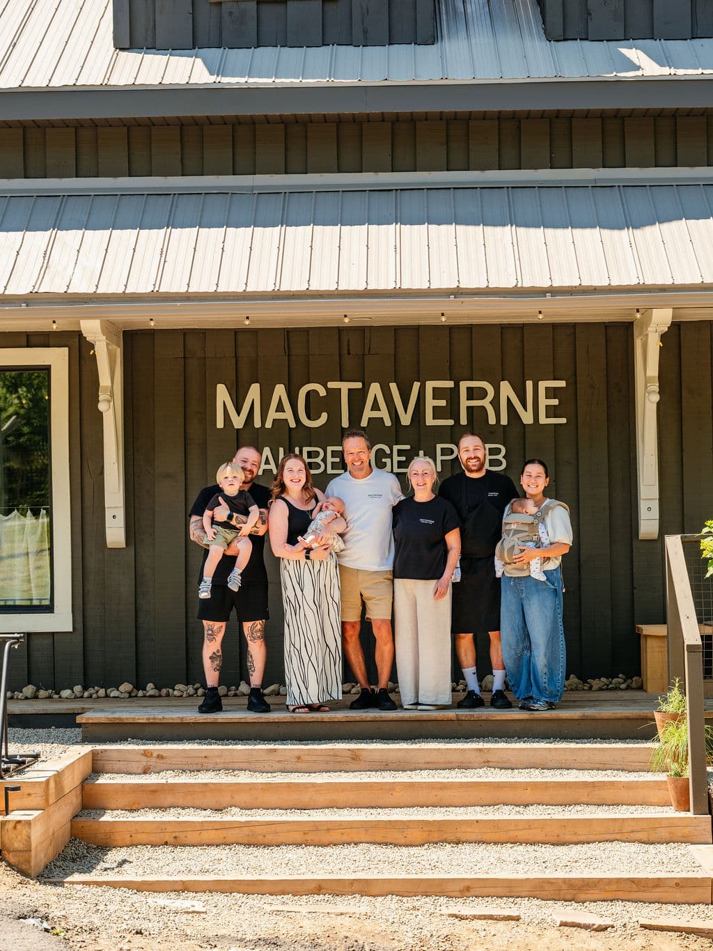 The Robertson family on the front steps of MacTaverne in Val-David, beneath the Auberge + Pub sign, a finalist for Air Canada's Best New Restaurants 2026